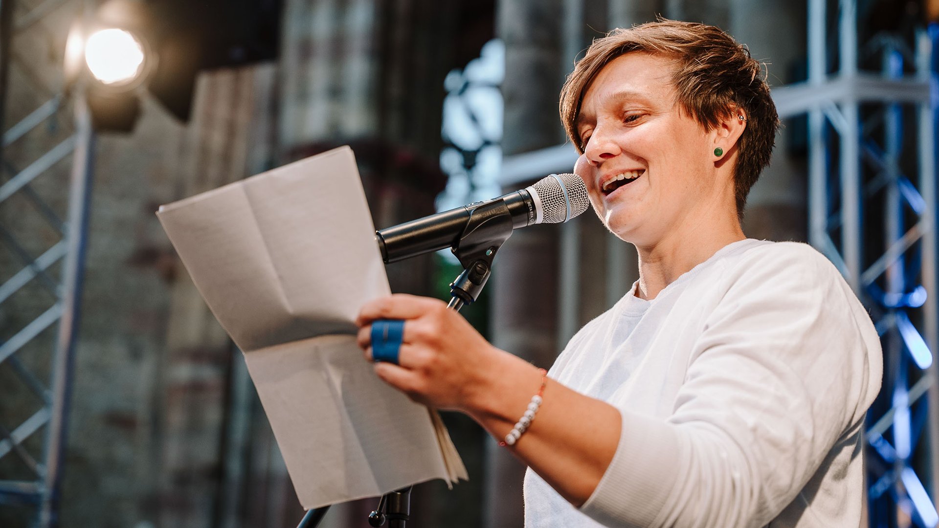 Foto für die Veranstaltung 9. Seeoner Poetry Slam mit einer Frau, die liest, und einem Mikrofon.
