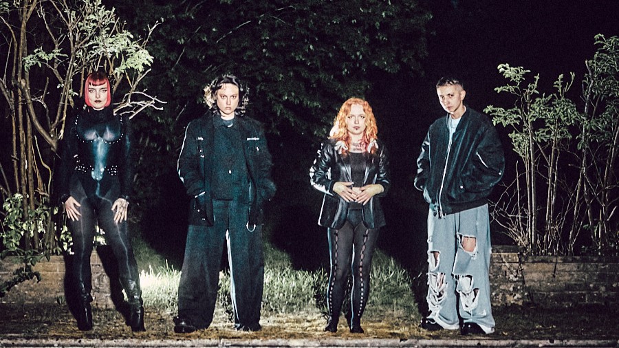 Ein Foto für das WITCH FEVER-Event mit der Gruppe zwischen Pflanzen in der Nacht