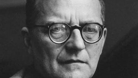 Schwarz-weiss einer Person mit Brille und starken Gläsern vor dunklem Hintergrund