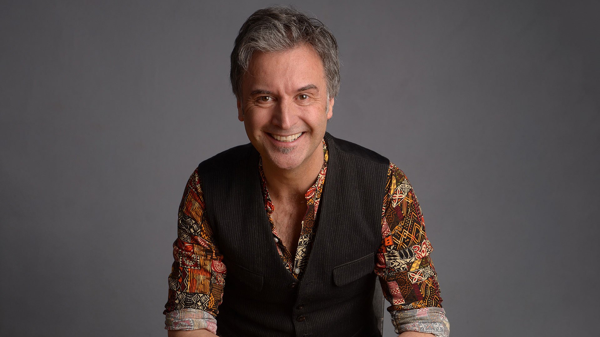 Foto für die Veranstaltung Chris Boettcher – Baby Boomer mit dem Künstler im geblümten Hemd vor grauem Hintergrund