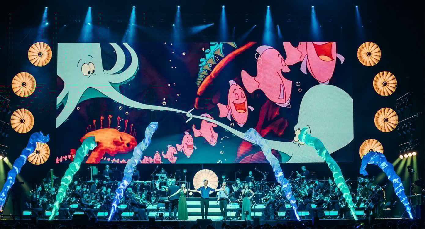 Orchester vor Leinwand auf der viele Tickfilm-Fische zu sehen sind