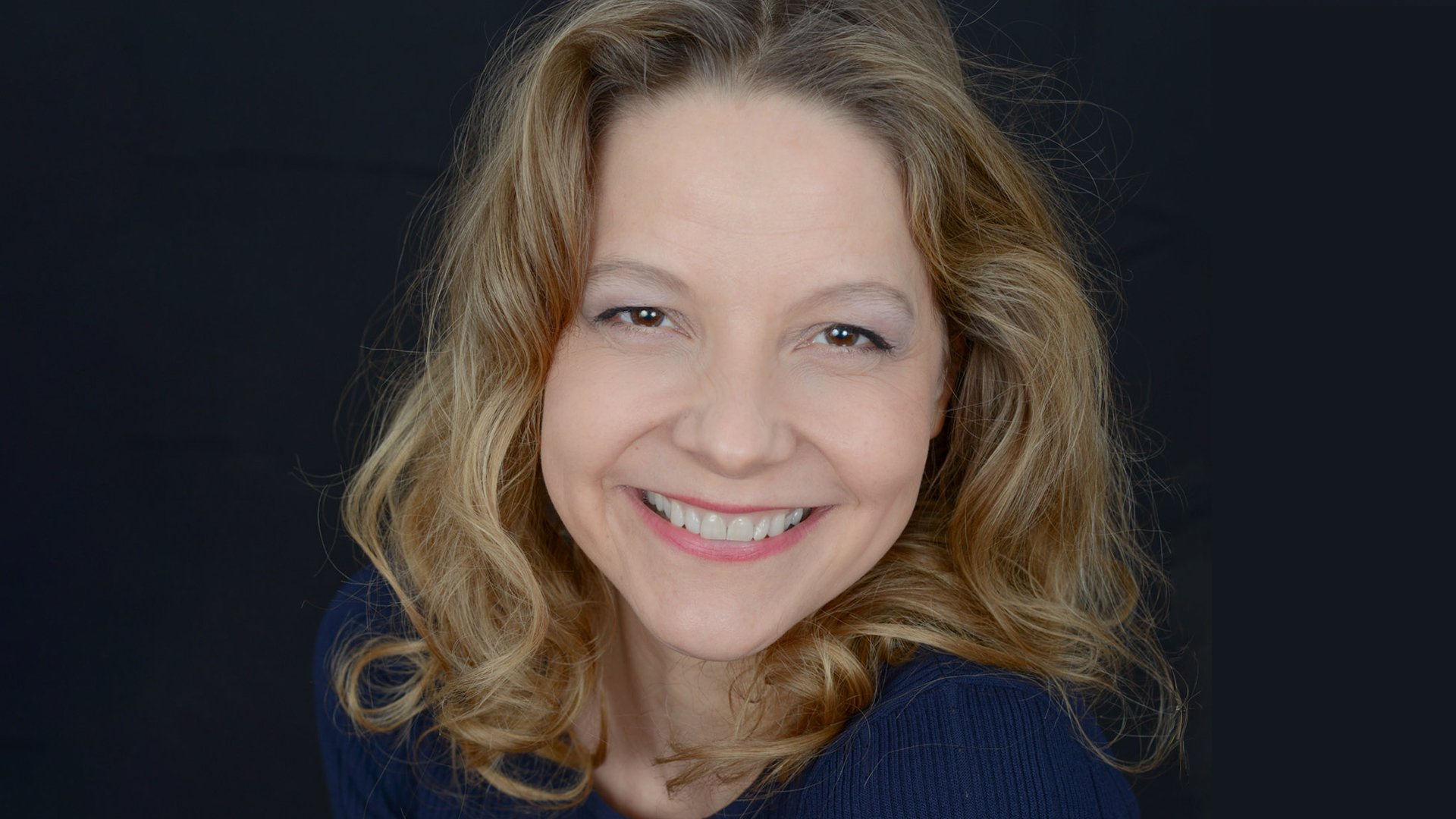 Bild einer blonden Dame vor dukelblauem Hintergrund