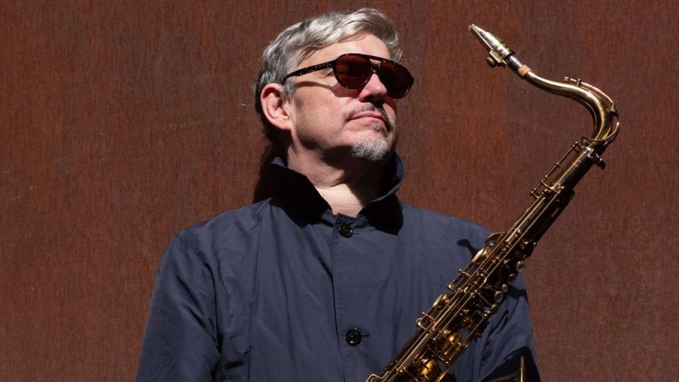 Foto für die Veranstaltung des J. Enders Quartet mit dem Künstler und einem Saxophon vor braunem Hintergrund