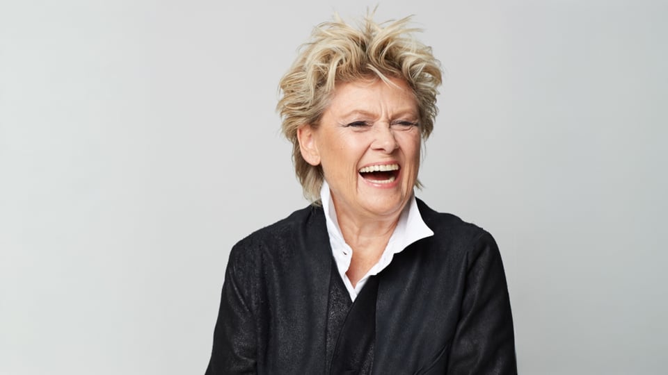 Gitte Haenning, dänische Sängerin, lächelt in einem Studio-Porträt mit kurzem blondem Haar und schwarzer Jacke vor hellem Hintergrund – Pressebild zum Konzert „Ich bin stark – 80 Jahre Gitte Haenning“