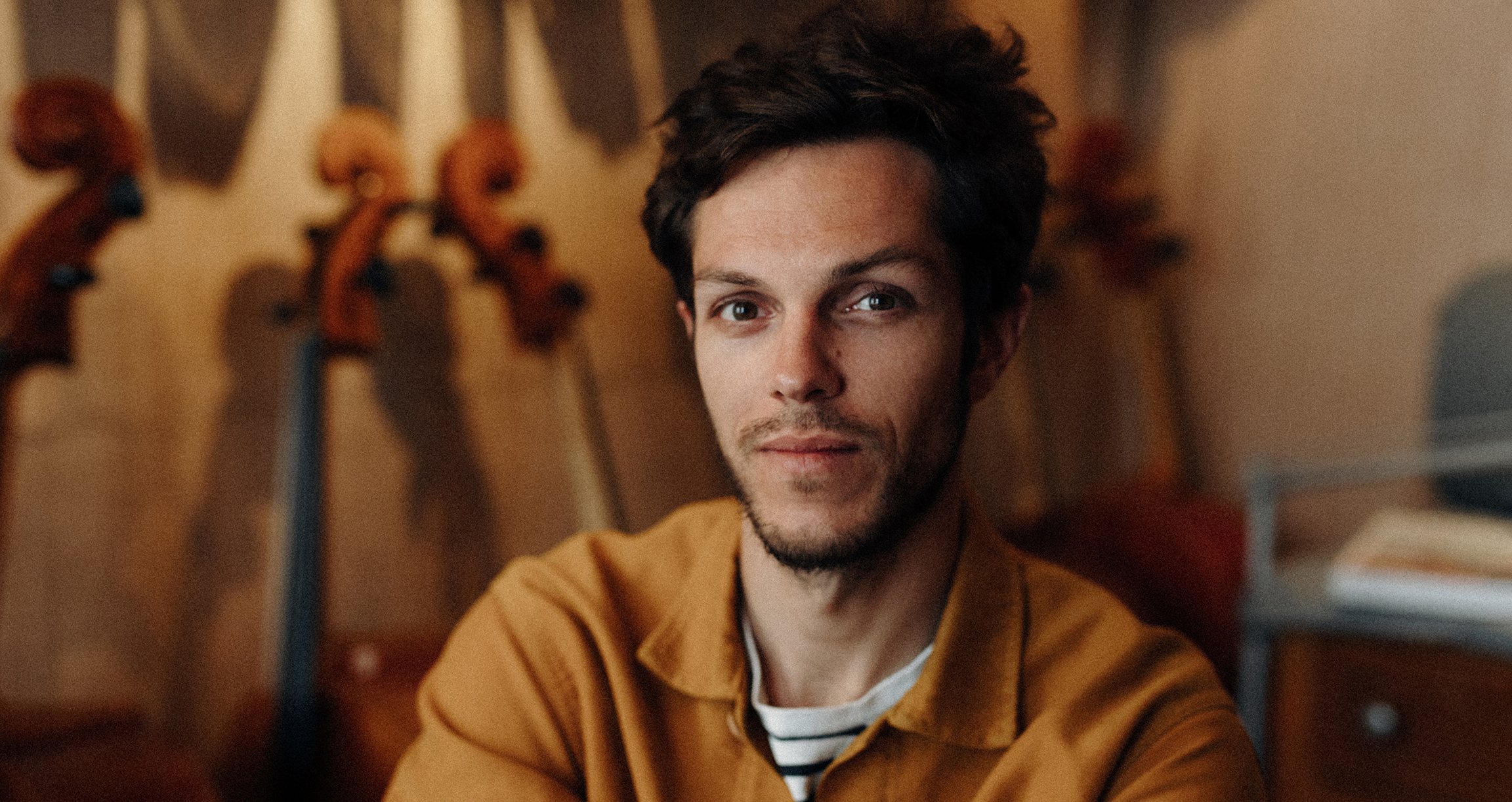 Foto eines männlichen Gesichts vor einem unscharfen Hintergrund mit Instrumenten