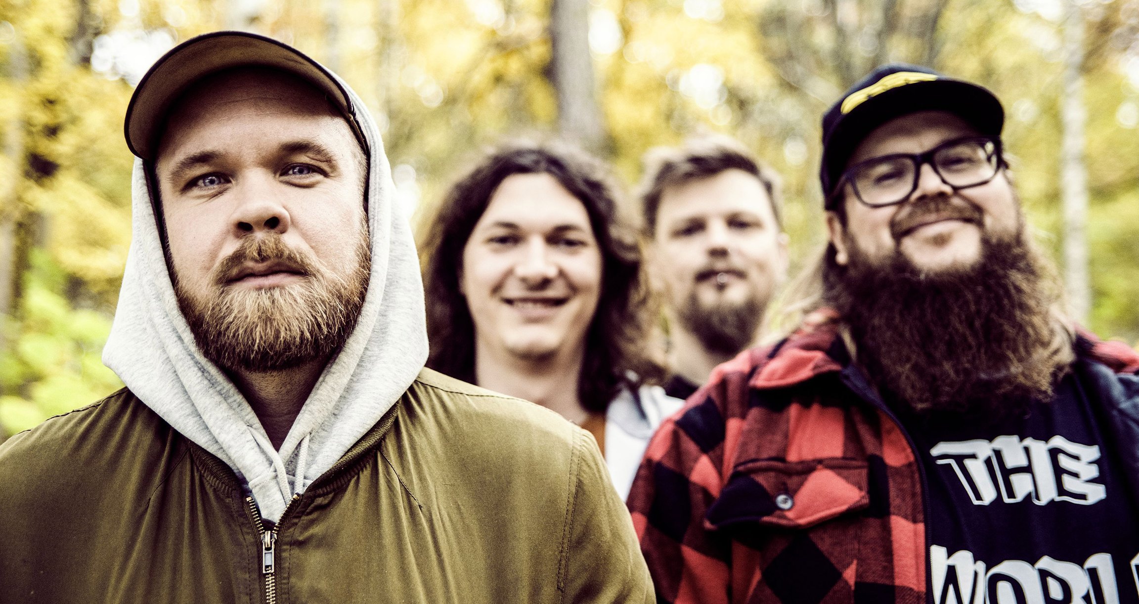 Foto der vier Bandmitglieder mit einem verschwommenen Wald im Hintergrund.