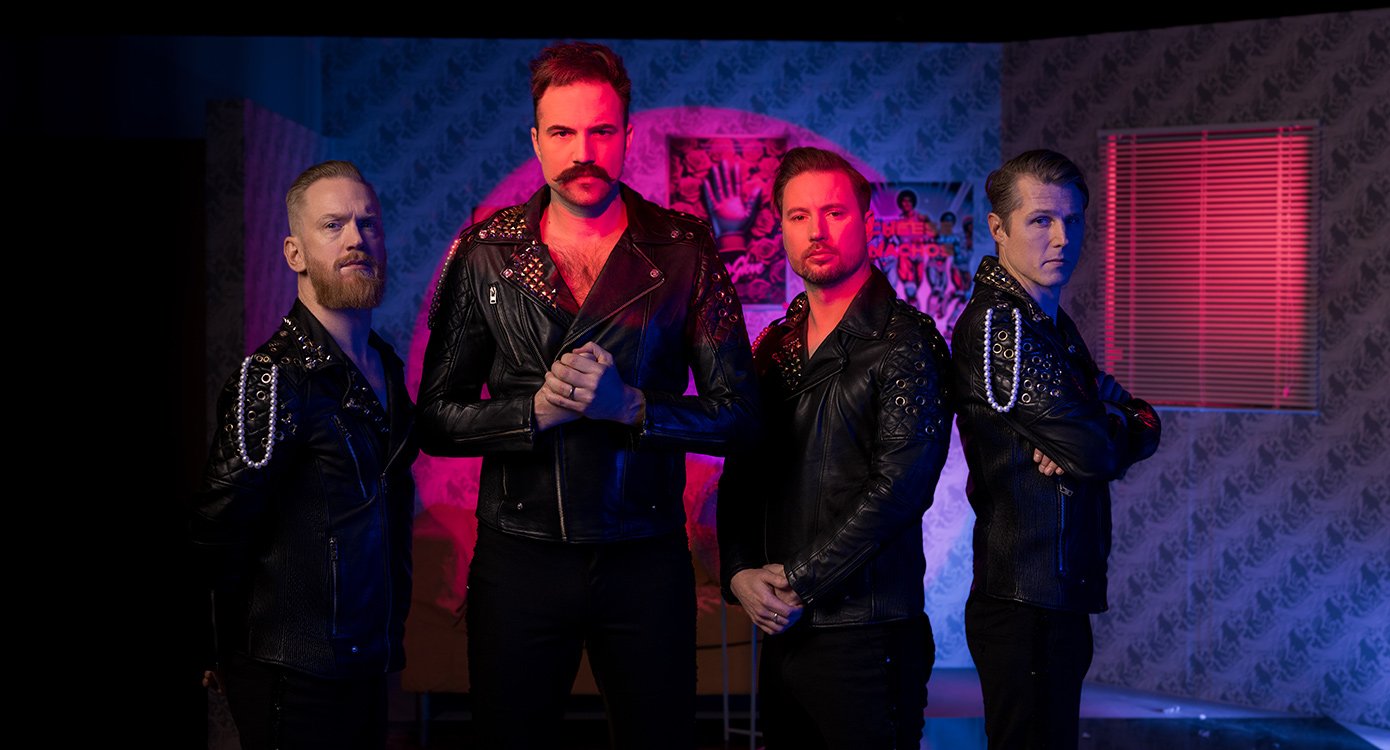 Vier Personen in schwarzen Lederjacken stehen vor rot und blau beleuchtetem Hintergrund