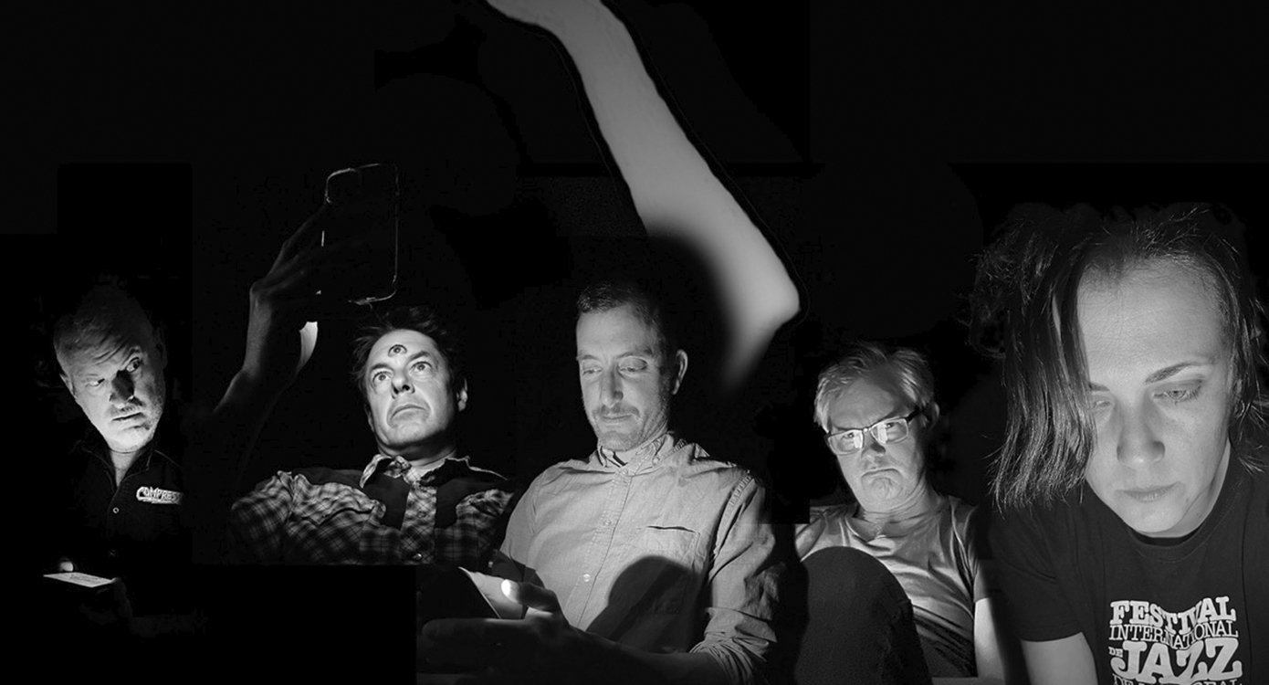 Schwarz-Weiß-Foto mit fünf Männern, die sitzen und auf ihre Handys schauen.