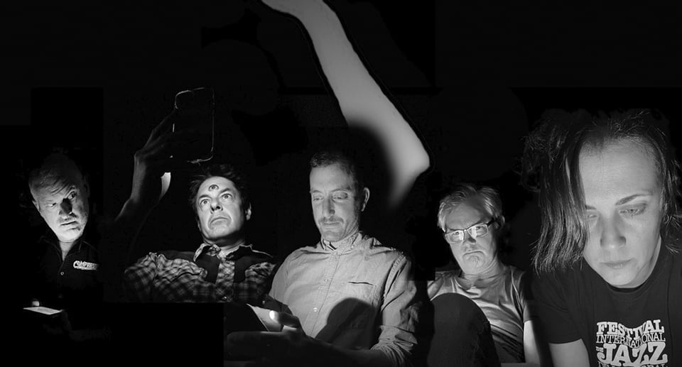 Schwarz-Weiß-Foto mit fünf Männern, die sitzen und auf ihre Handys schauen.