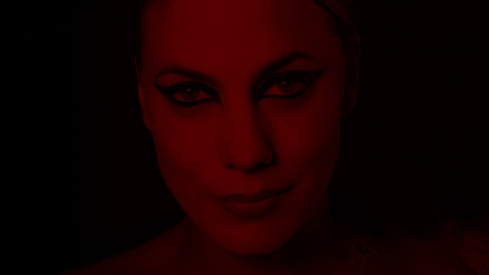 Ein Portrait der Künstlerin Lafee mit stark geschminkten Augen, ihr Gesicht in dunklem rot mit dunklem Hintergrund 