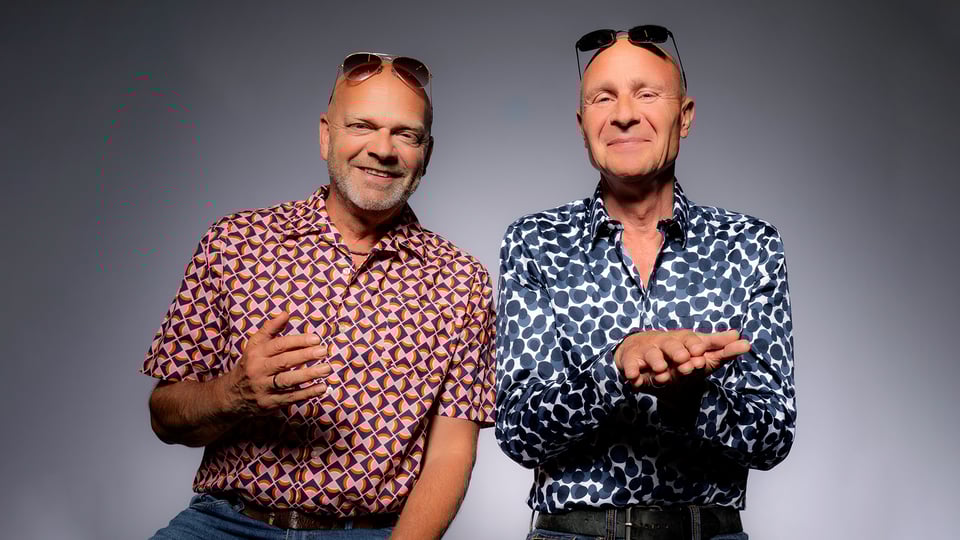 Zwei Herren in bunt gemusterten Hemden gestikulieren und lächeln