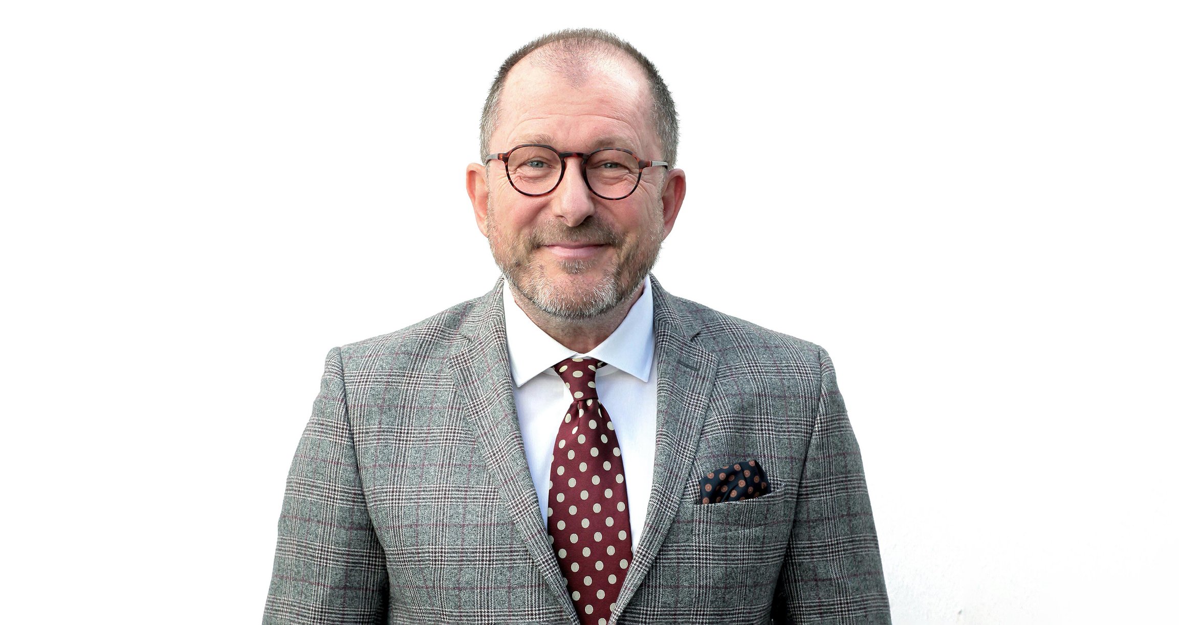 ein Herr in einer grauen Anzugsjacke mit Krawatte auf weißem Hintergrund