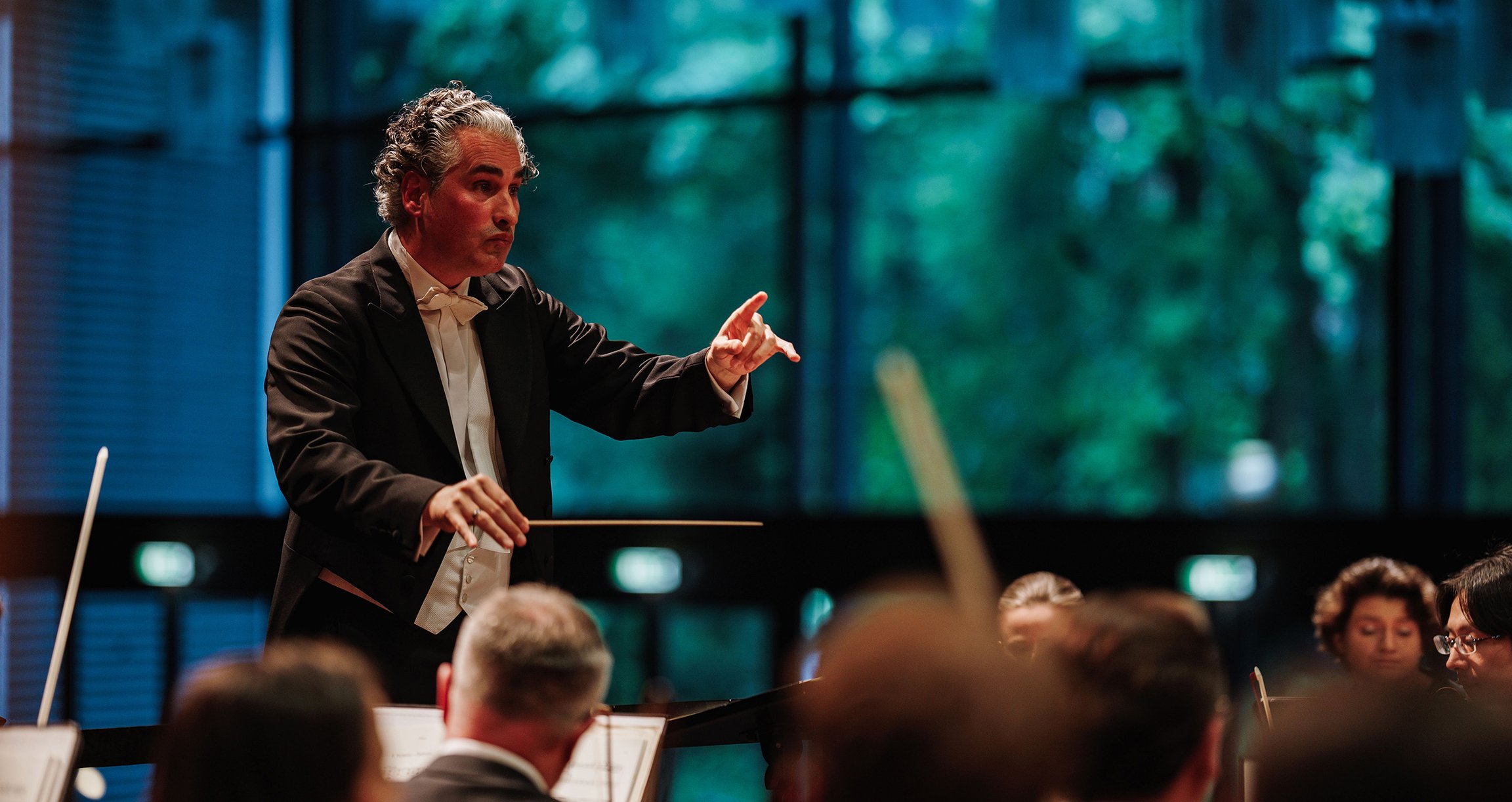 ein Dirigent steht zu seinem Orchester