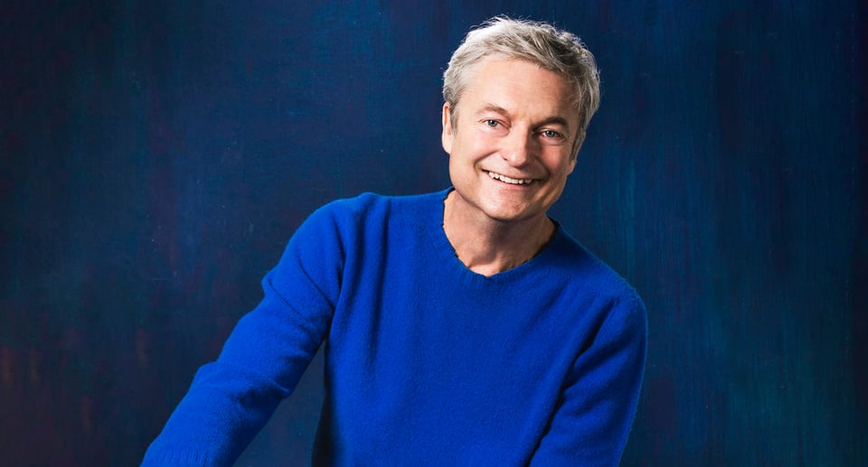 Foto des Künstlers mit blauem Pullover vor blauem Hintergrund.