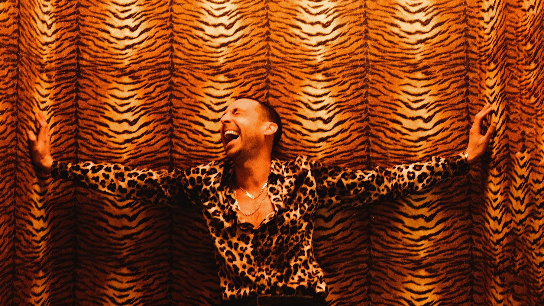 Miles Kane beim Event – mit Leopardenhemd vor Tigermuster-Hintergrund.
