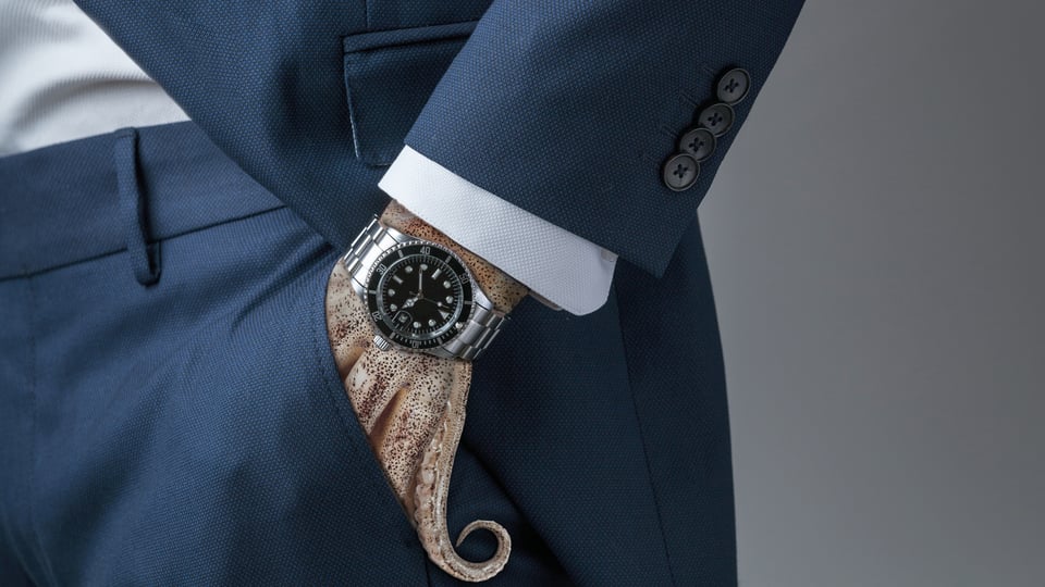 Foto für die Veranstaltung Geld.Gier.Macht mit einem Bild einer Hand in Form von Tentakeln, die in einer Tasche steckt