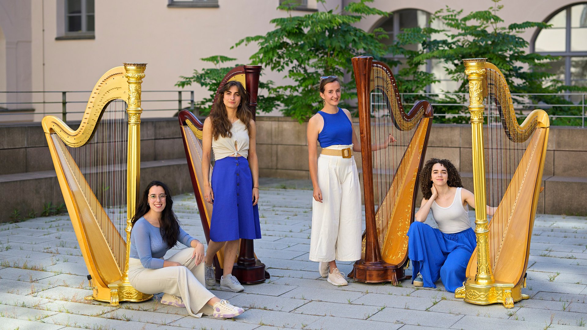 Foto für die Veranstaltung ‚Münchner Harfenquartett‘ mit vier Frauen in blau-weißer Kleidung und drei Harfen