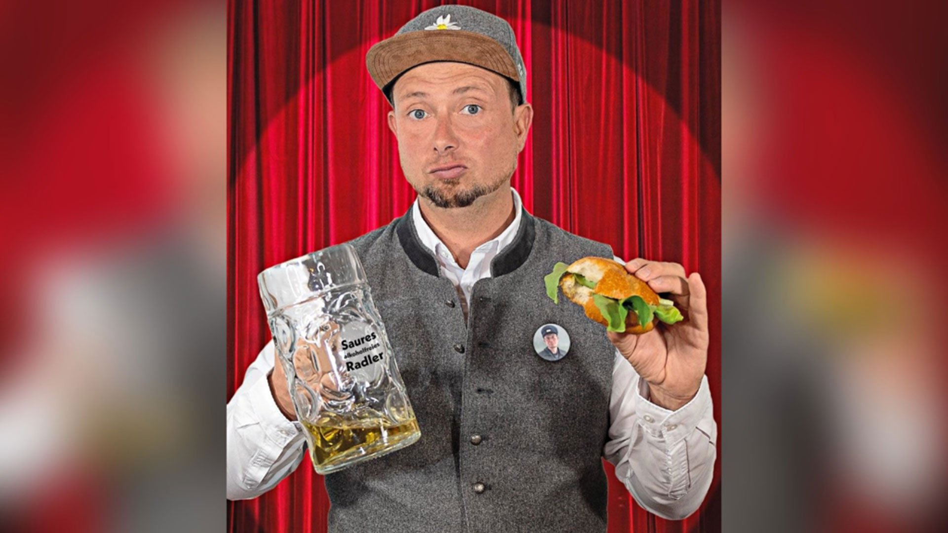 Foto des Künstlers mit einem Bier und einem Semmel, im Hintergrund rote Vorhänge.