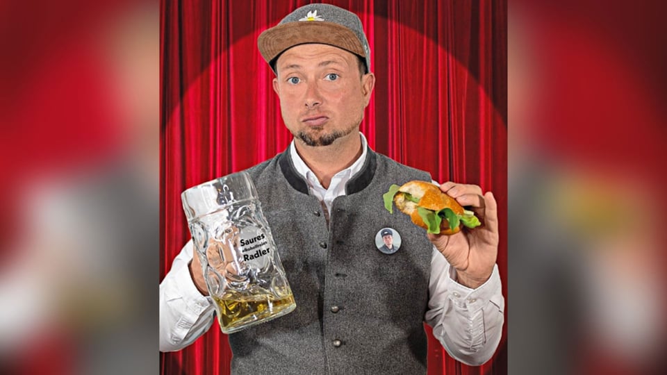 Foto des Künstlers mit einem Bier und einem Semmel, im Hintergrund rote Vorhänge.