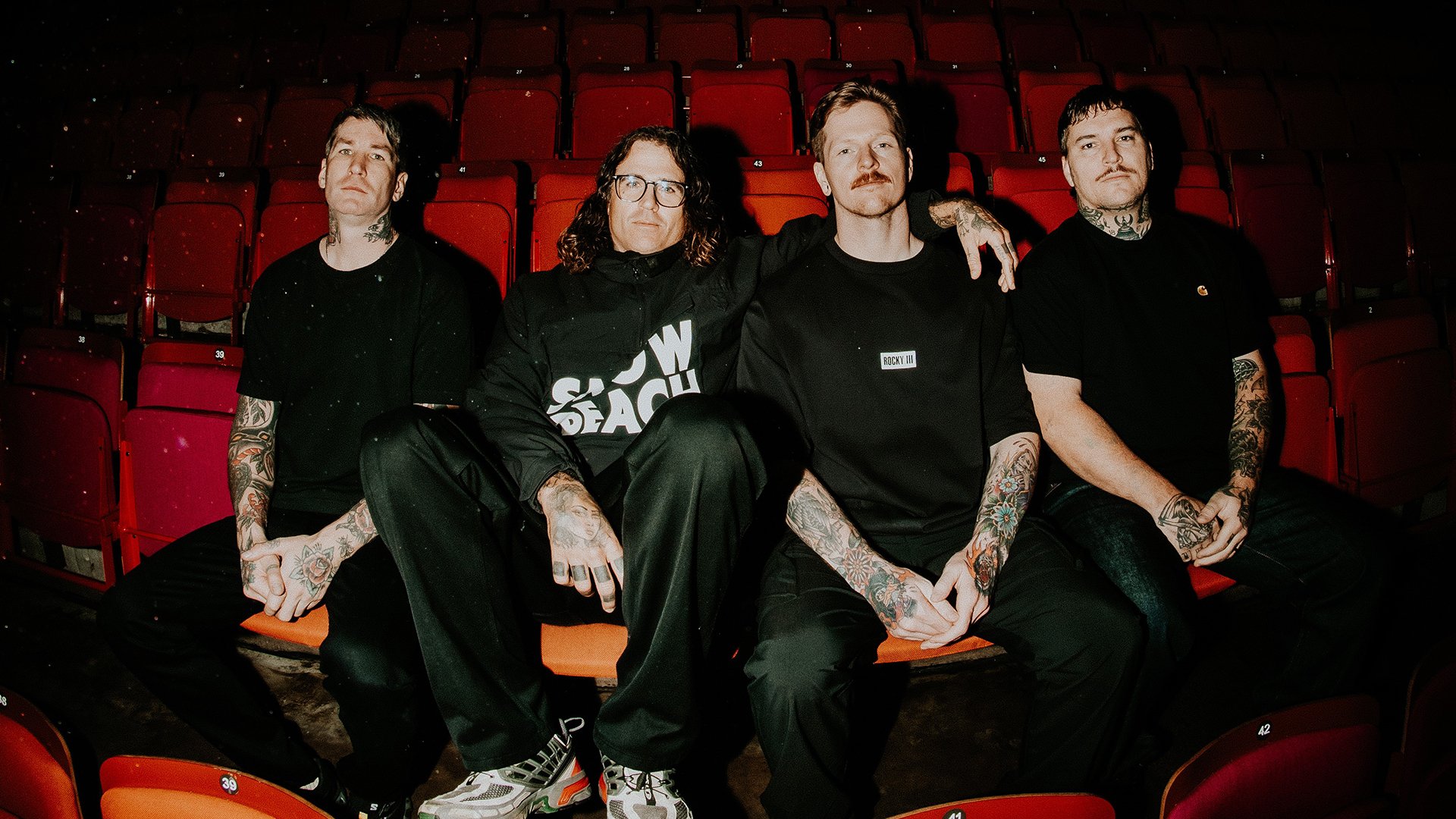 Die vier Bandmitglieder von The Amity Affliction auf den roten Sitzen eines Kinosaals