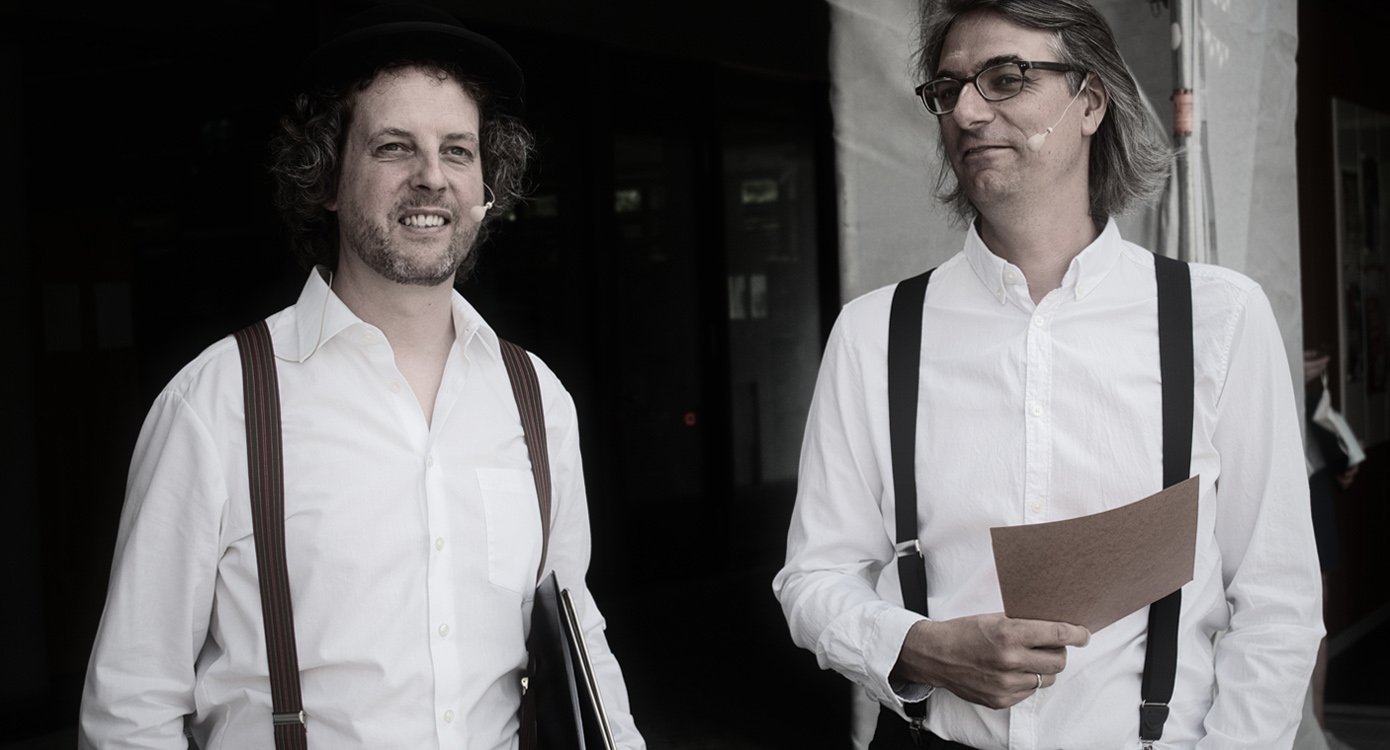 Ein Foto der beiden Dartseller in weißen hemden und Hosenträgern