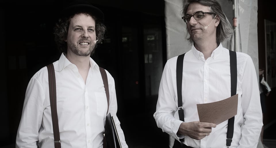 Ein Foto der beiden Dartseller in weißen hemden und Hosenträgern