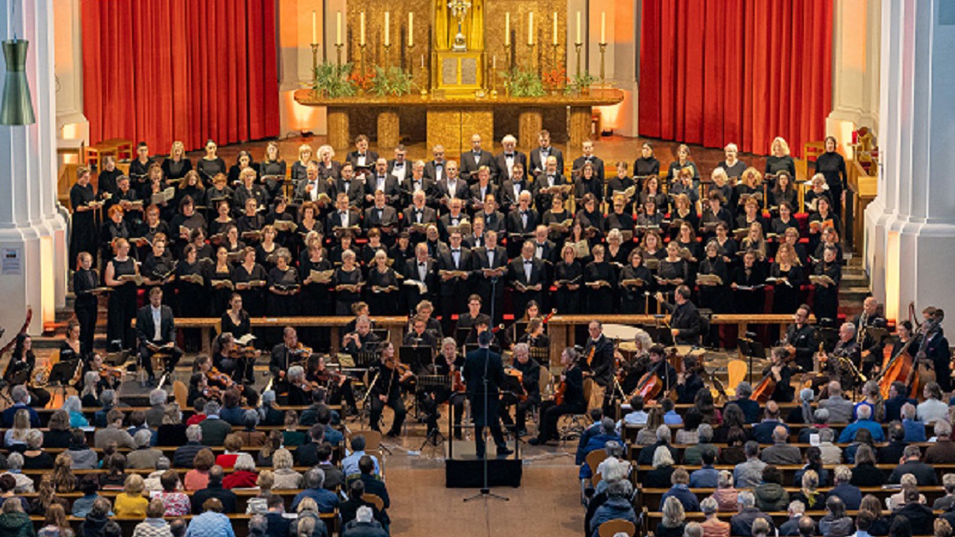 Der St.Josephschor München mit Publikum, im Hintergrund ein Altar 