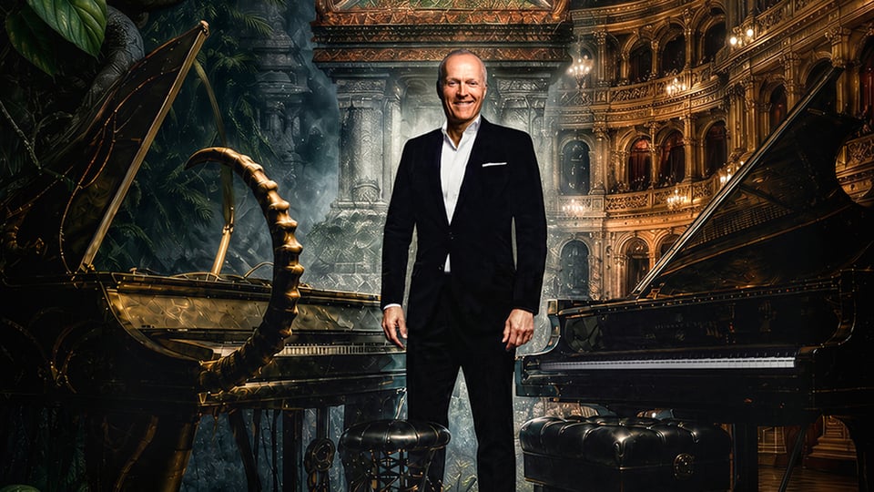 Joja Wendt im dunklen Anzug zwischen zwei Konzertflügeln, vor einer opulenten Theaterkulisse mit Säulen, Logen und warmem Bühnenlicht