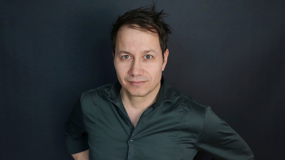 Porträt des Künstlers Marco Tschirpke vor dunklem Hintergrund zum Programm „Empirisch belegte Brötchen“.