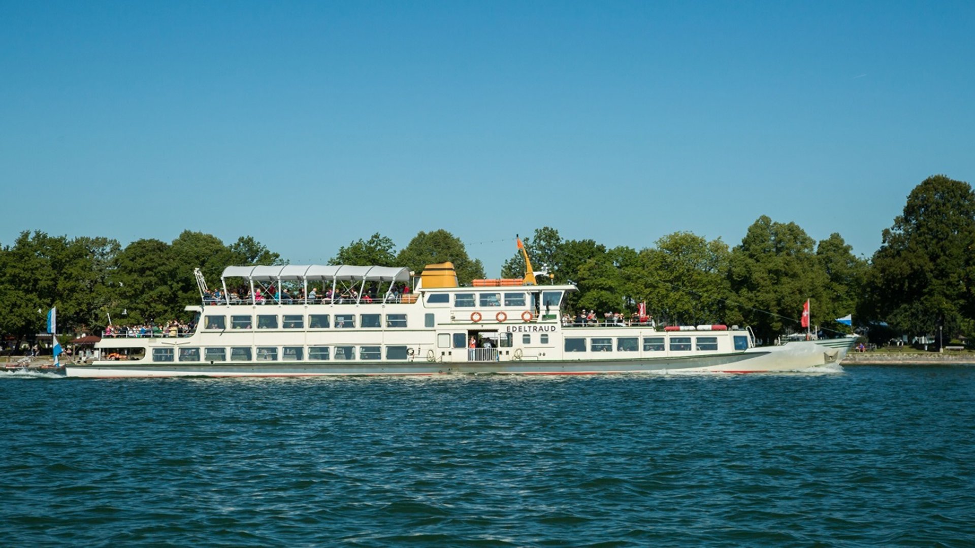 EIn Schiff mit zahlreichen Personen an Deck auf dem Wasser