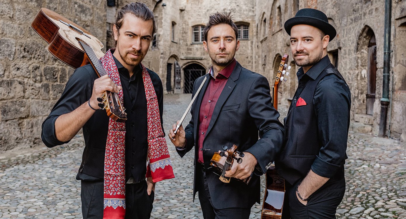 Foto der drei Musiker mit ihren Instrumenten in der Mitte einer Steinstraße