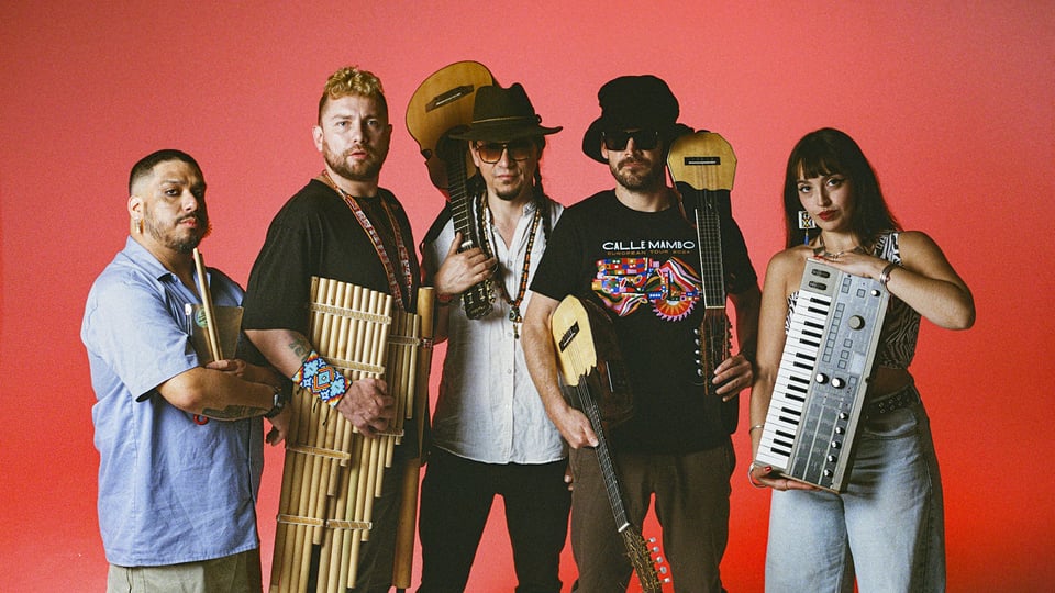 Fünf Personen mit traditionellen Instrumenten vor rotem Hintergrund