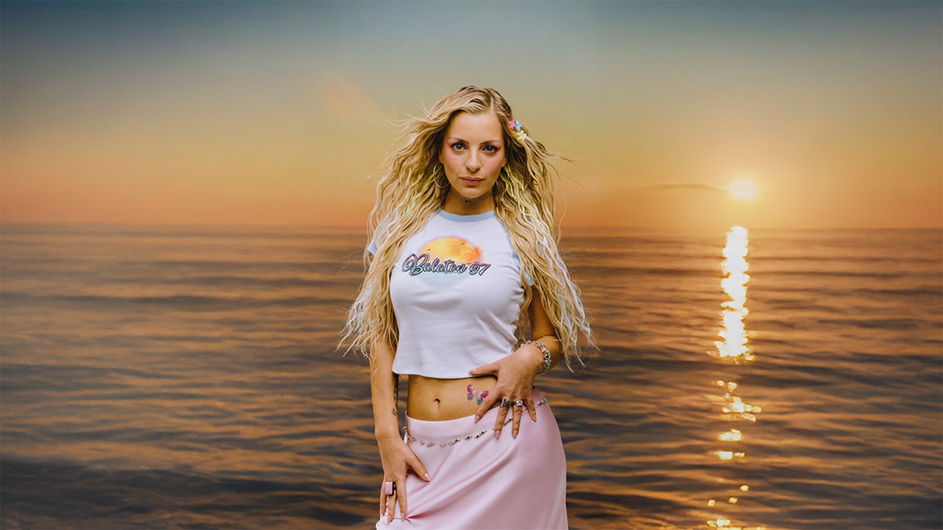 Foto von Laura Larsson vor einem Meer mit Sonnenuntergang im Hintergrund.