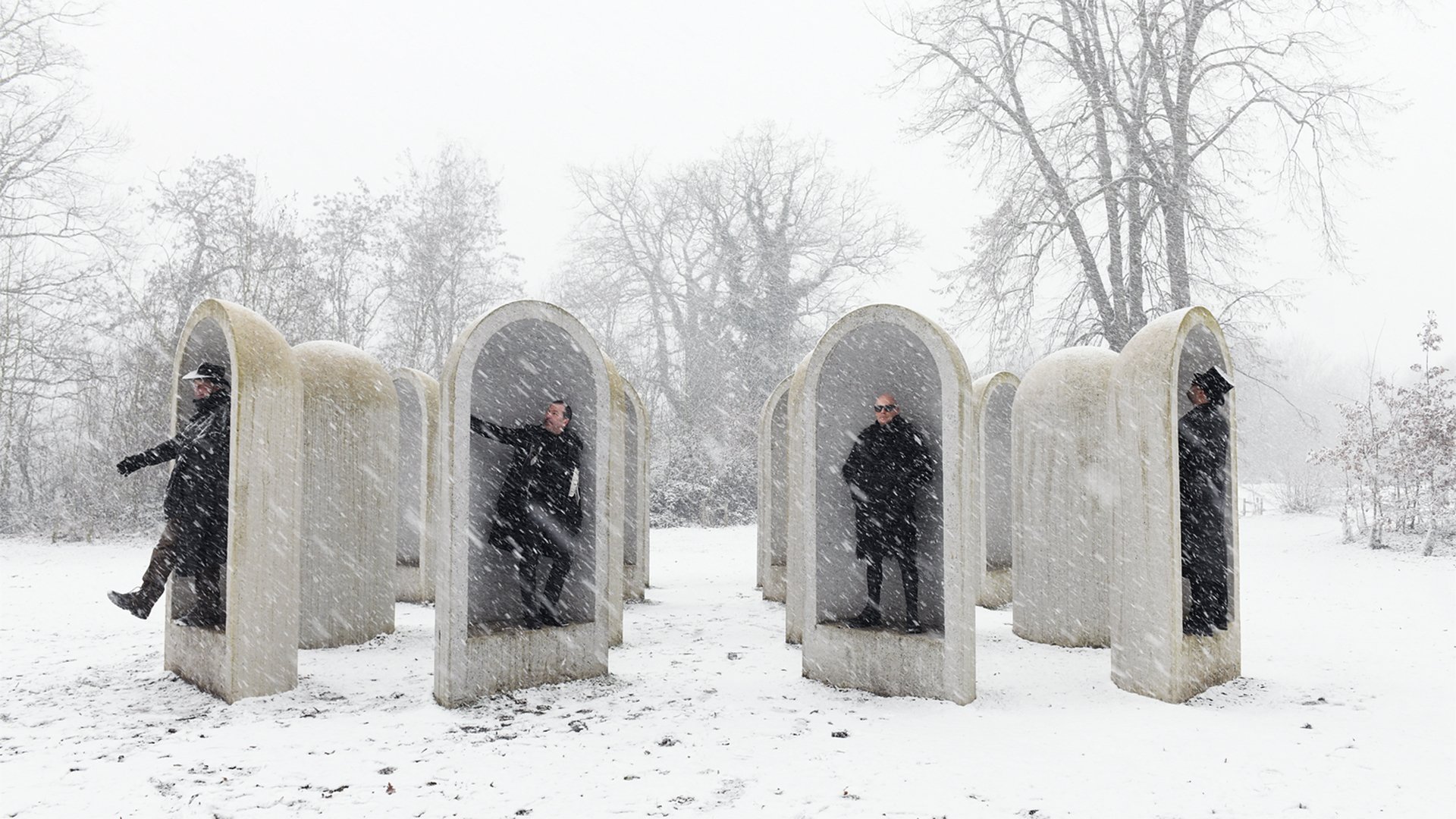 Die vier Bandmitglieder in einer winterlichen Szene in vier Umfassungsmauern stehend
