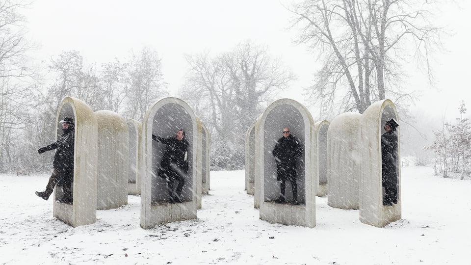 Die vier Bandmitglieder in einer winterlichen Szene in vier Umfassungsmauern stehend