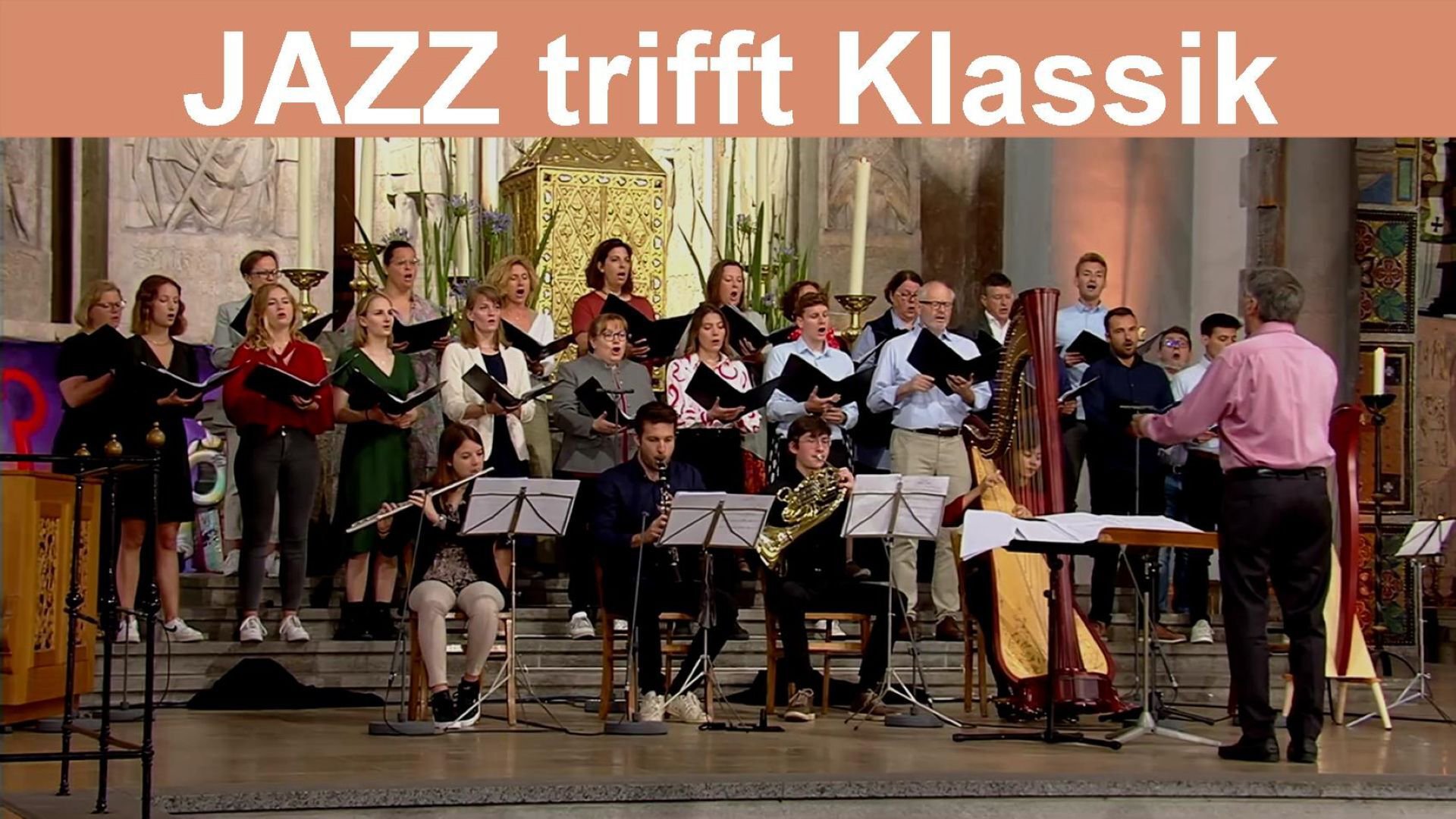 Konzertaufführung Jazz trifft Klassik in einer Kirche: Chor und Ensemble mit Blasinstrumenten und Harfe auf der Bühne, dirigiert vor dem Altarraum