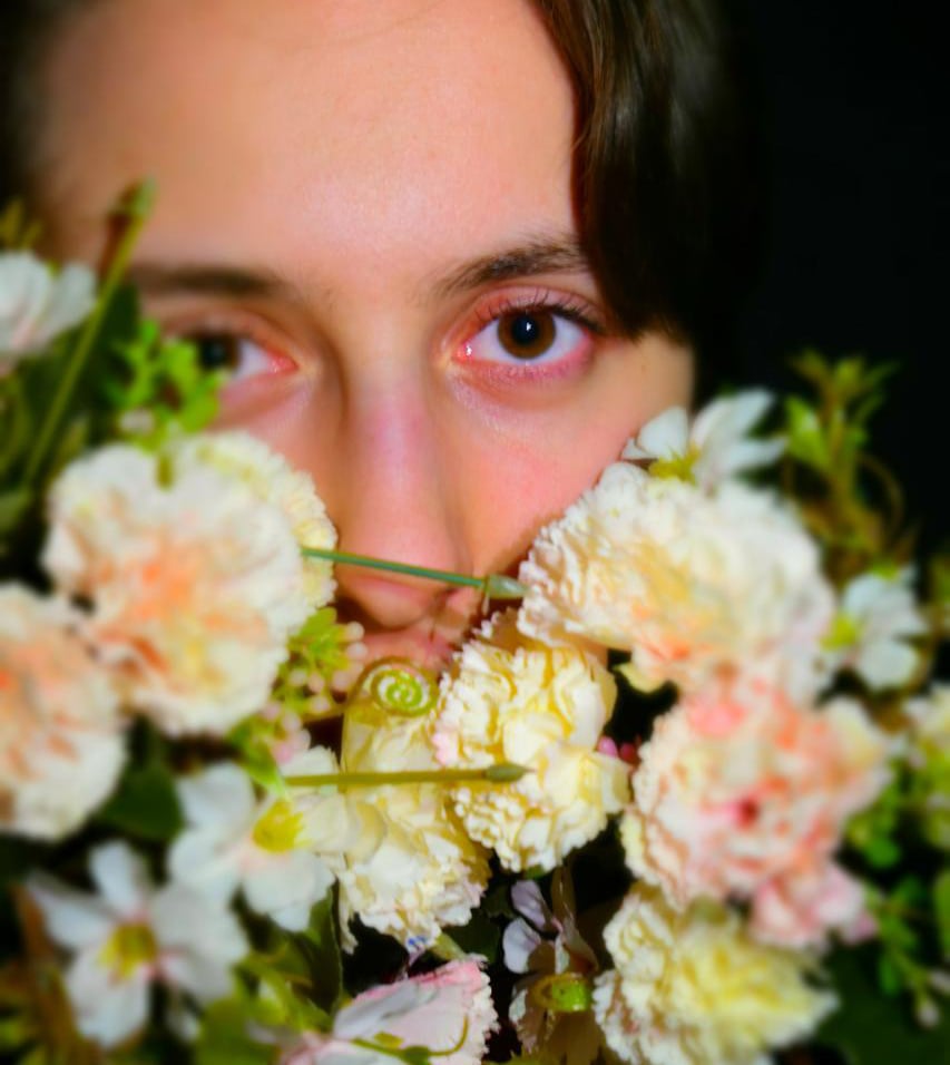 das Gesicht eines Mädchens hinter einigen Blumen