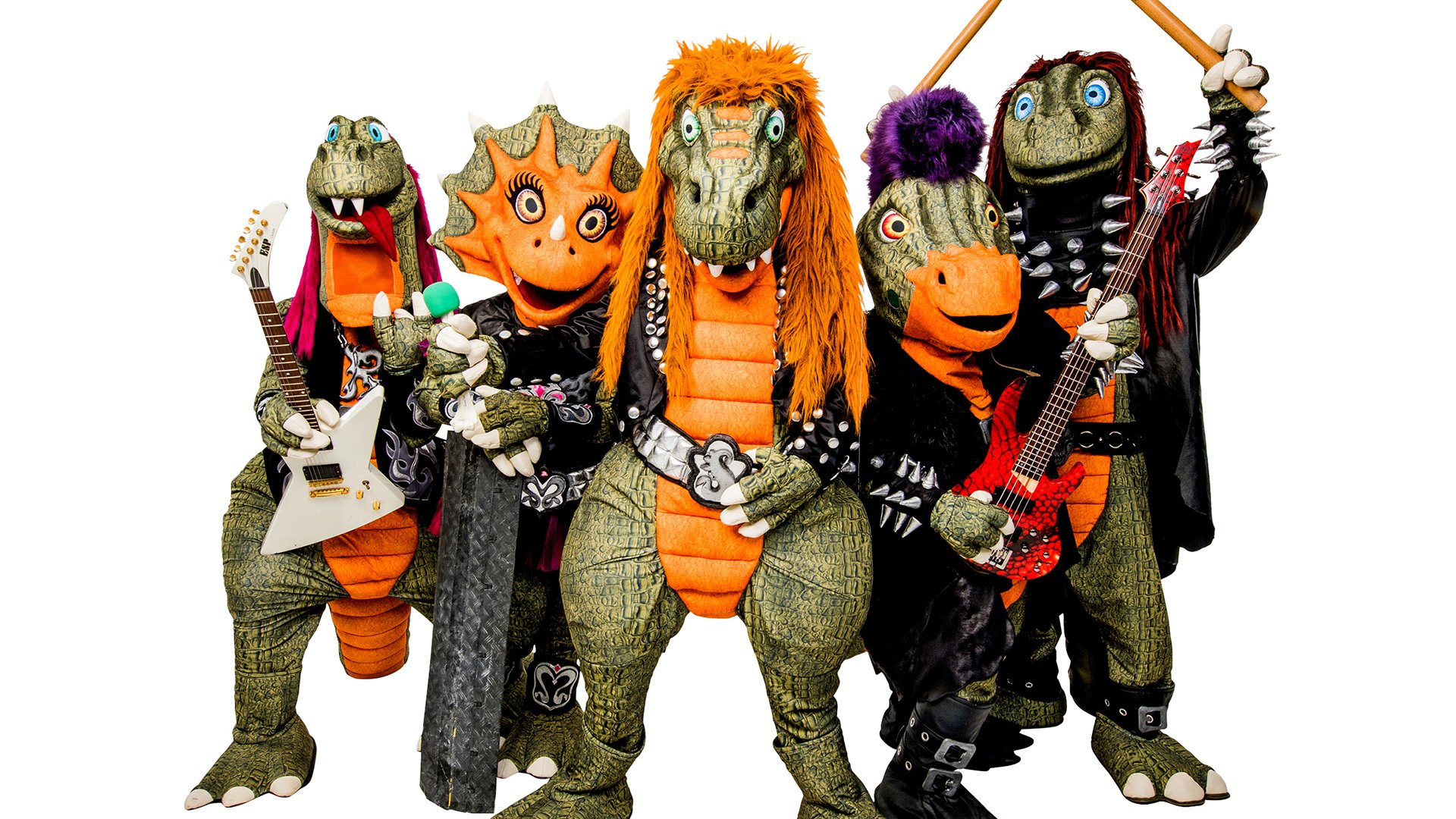 Pressefoto von Heavysaurus mit fünf Dinosaurierfiguren in Rockkostümen vor hellem Hintergrund, darunter E-Gitarren und Drumsticks, mit bunten Haaren, Nieten und schwarzen Bühnenoutfits