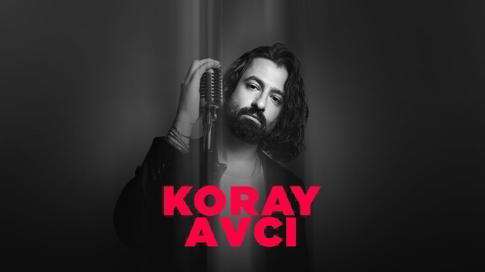 Schwarz weiss Portrait von Koray Avci mit langem Haar und Bart vor dunklem Hintergrund, eine Hand hält ein Mikrofon, roter Schriftzug des Namens im Vordergrund