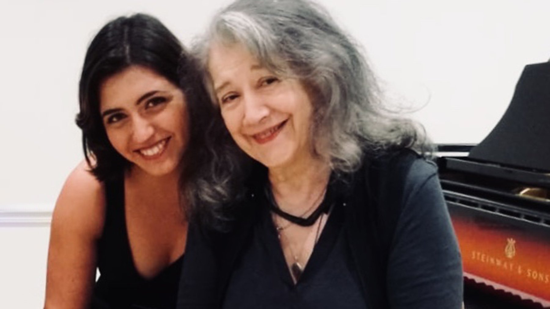 Zwei Künstlerinnen sitzen lachend an einem Konzertflügel