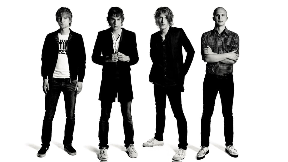 Vierköpfige Indie-Rockband in Schwarz-Weiß, stehende Ganzkörperaufnahme vor hellem Hintergrund