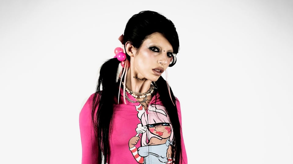 Schwarzhaarige Dame in pink-buntem Oberteil und mit pinkem Haarschmuck