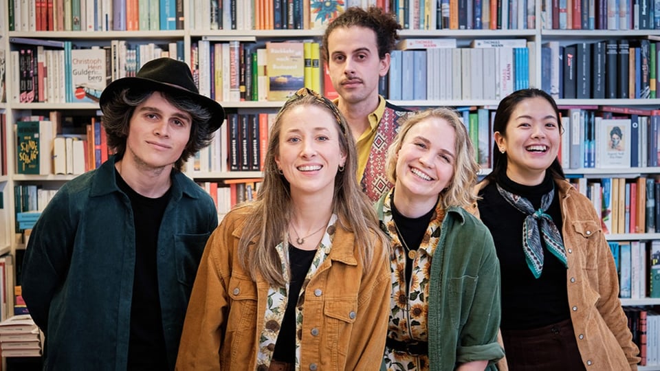 Die fünf Bandmitglieder vor einem gefüllten Bücherregal 