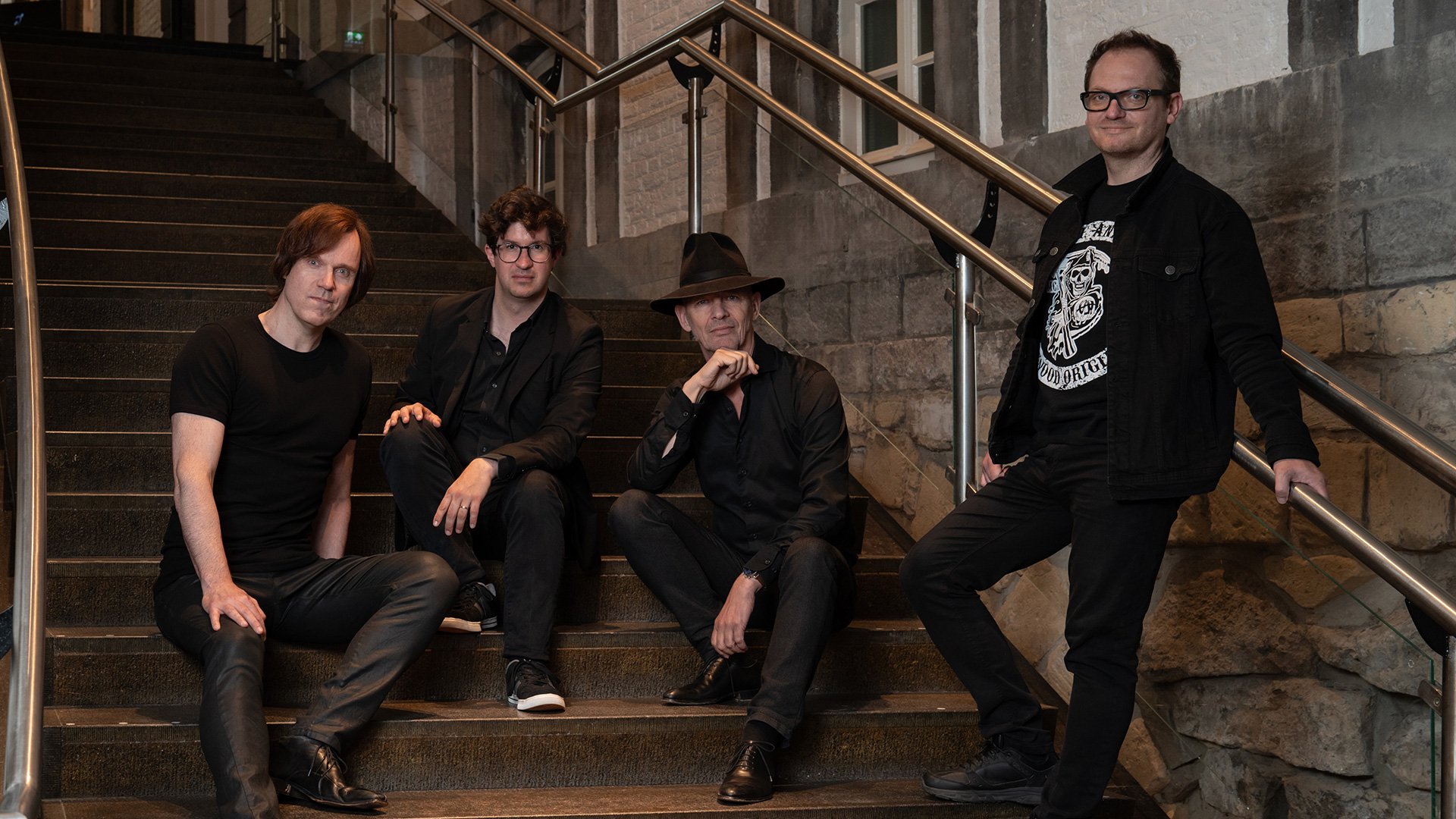 Foto für die Veranstaltung Vokal Total – Rock4, mit den Künstlern, die auf einer Treppe sitzen