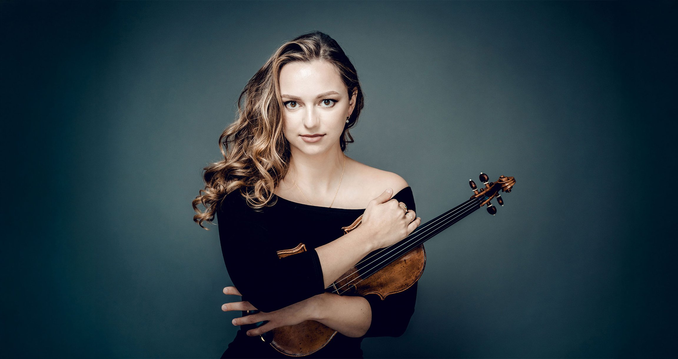 Dame mit Violine in schwarzer Kleidung vor dunkelblauem Hintergrund