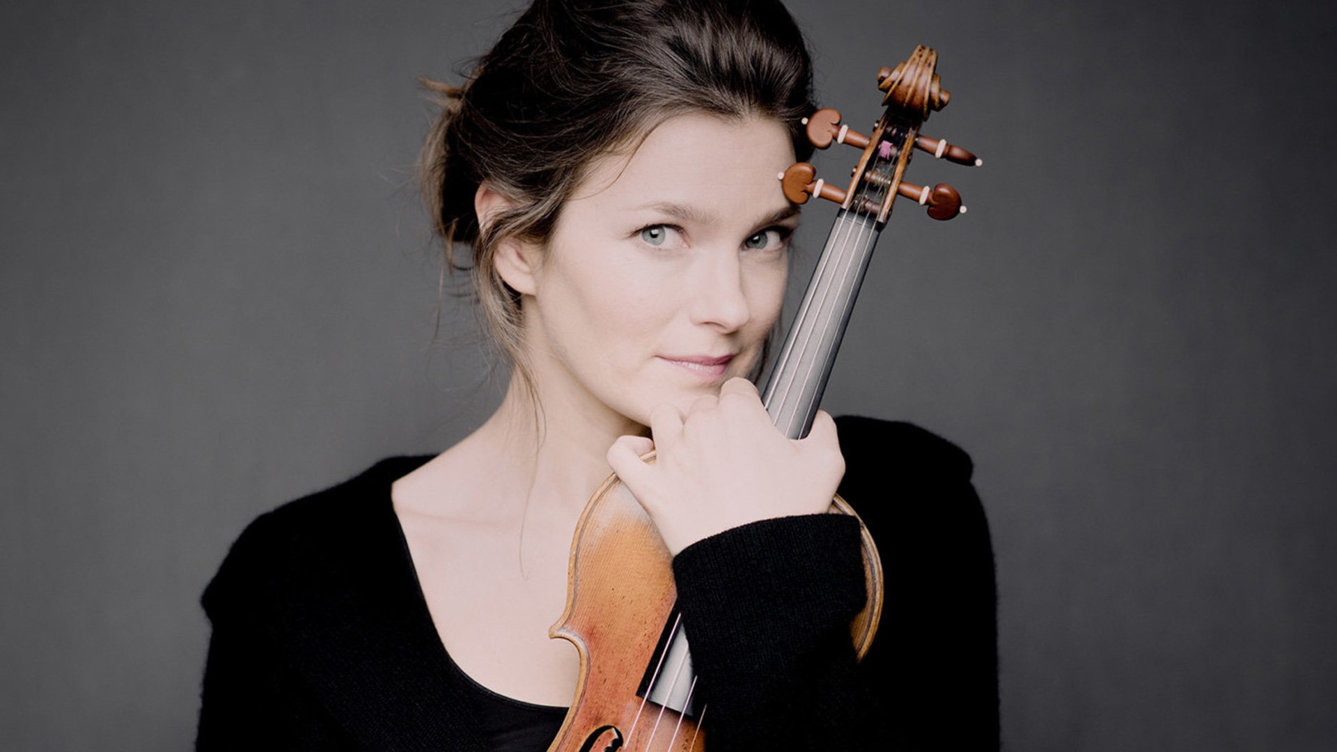 Foto von der Künstlerin Janine Jansen mit einer Violine vor grauem Hintergrund