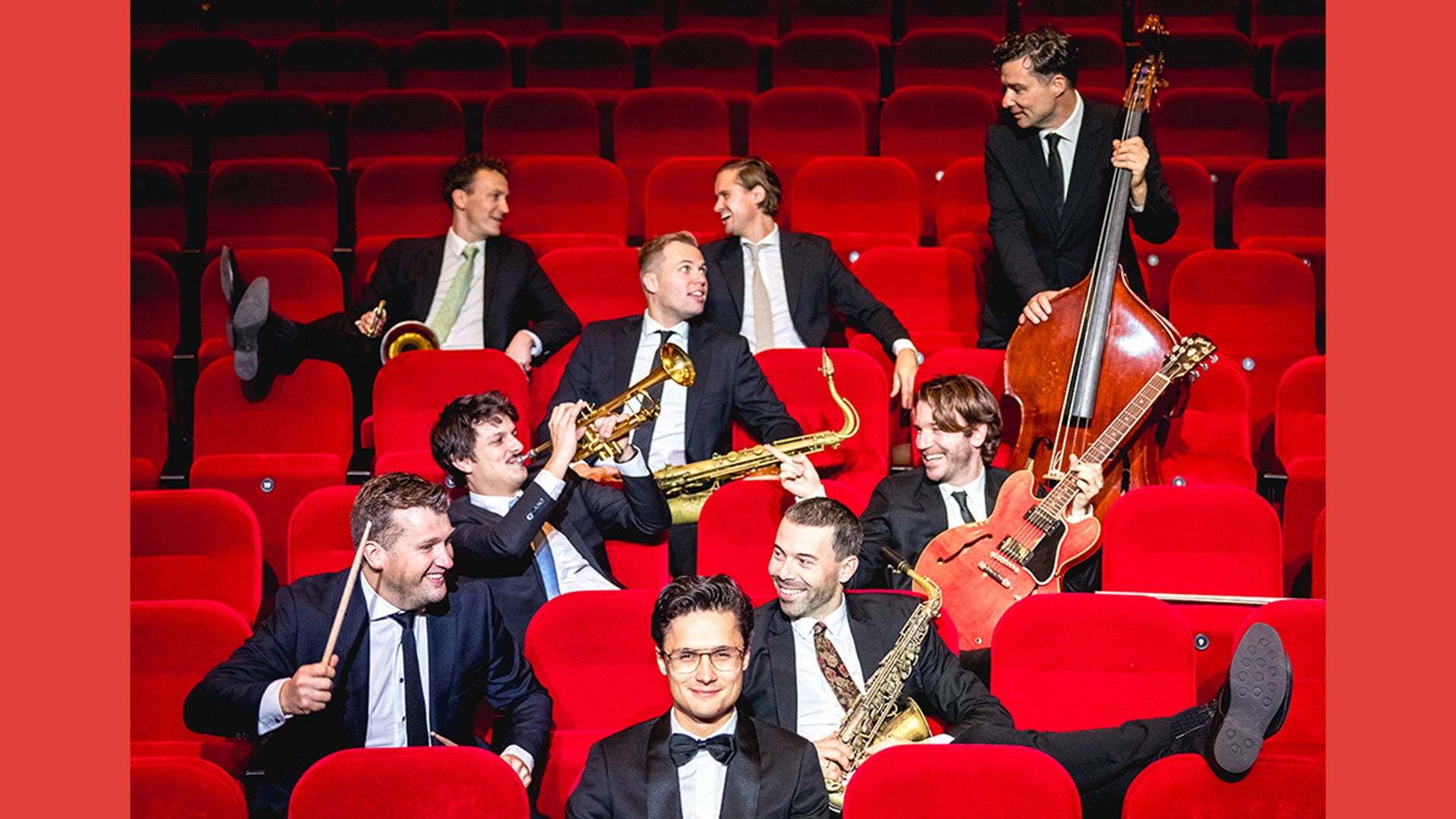 Foto für die Veranstaltung "DENNIS VAN AARSSEN & die DVA Bigband", mit den Künstlern auf roten Sesseln sitzend.