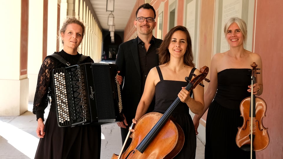 Vier Musiker:innen in schwarzer Kleidung stehen in einem Arkadengang; eine Person hält ein Akkordeon, zwei weitere ein Cello und eine Viola, im Hintergrund Säulen und warme Architektur.