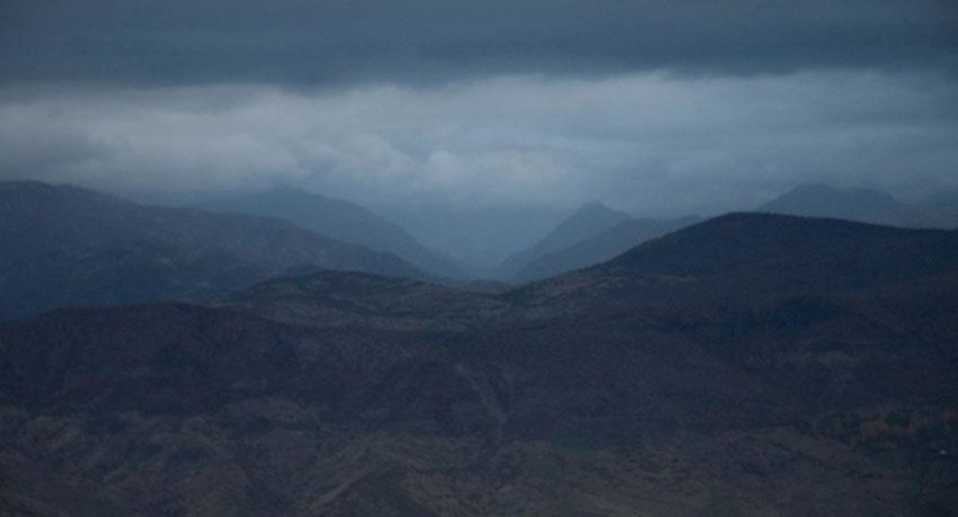 eine wolkenverhangene Landschaft mit Bergen und Wiesen