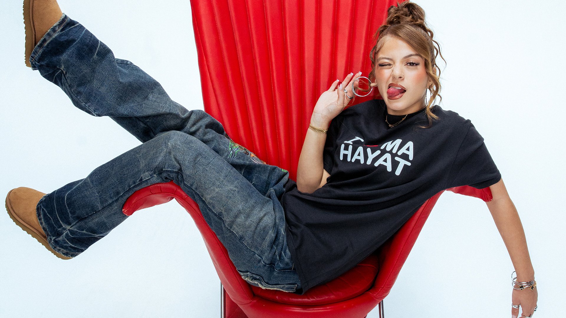 Ein Foto für die Veranstaltung ZAH1DE mit der Künstlerin auf einem roten Sessel vor weißem Hintergrund